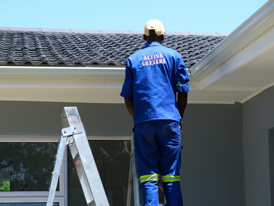 An Action Gutters installer fitting a seamless aluminium gutter on a home in Gqeberha